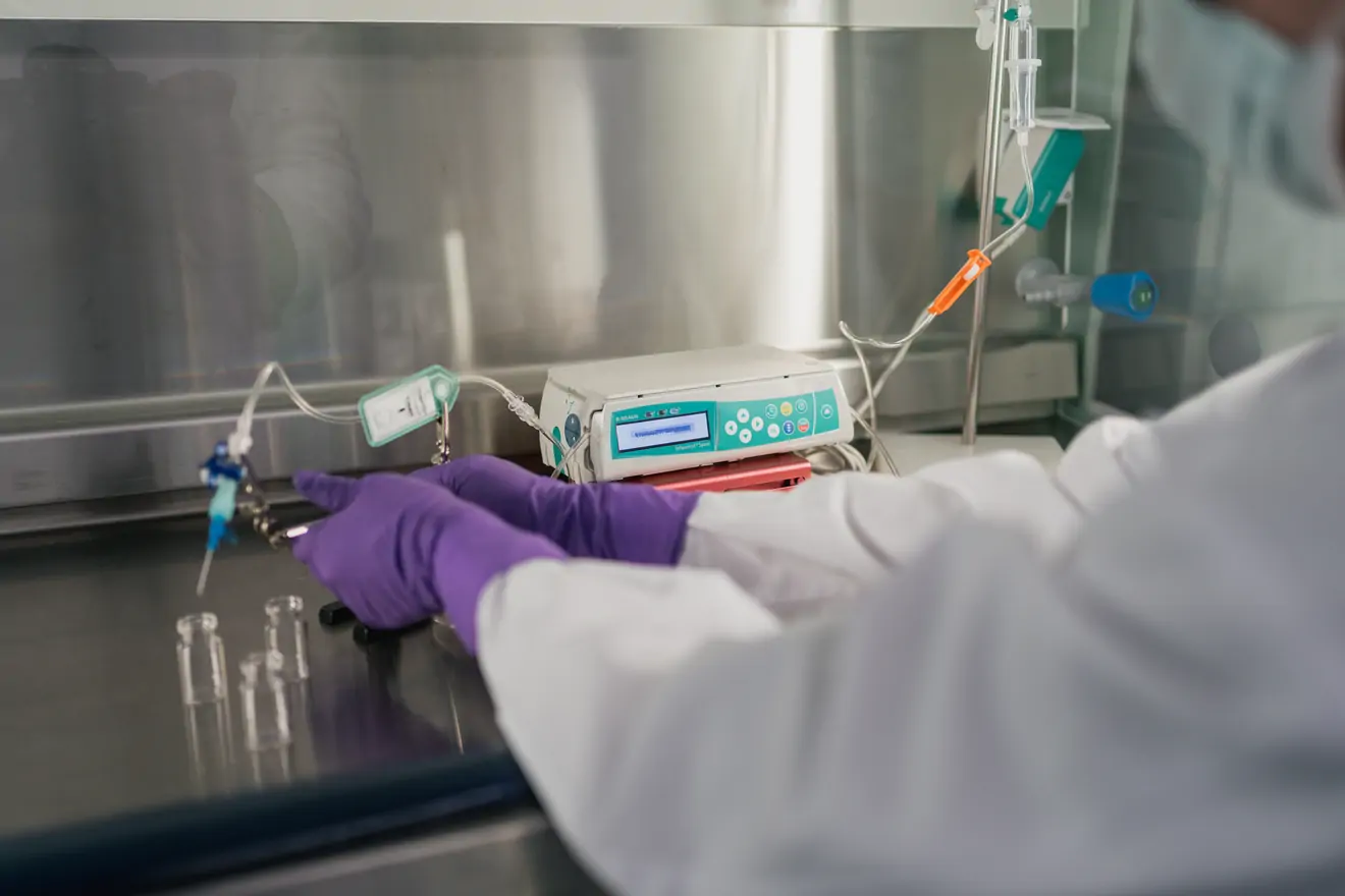 a technician uses a machine to fill vials with a liquid substance